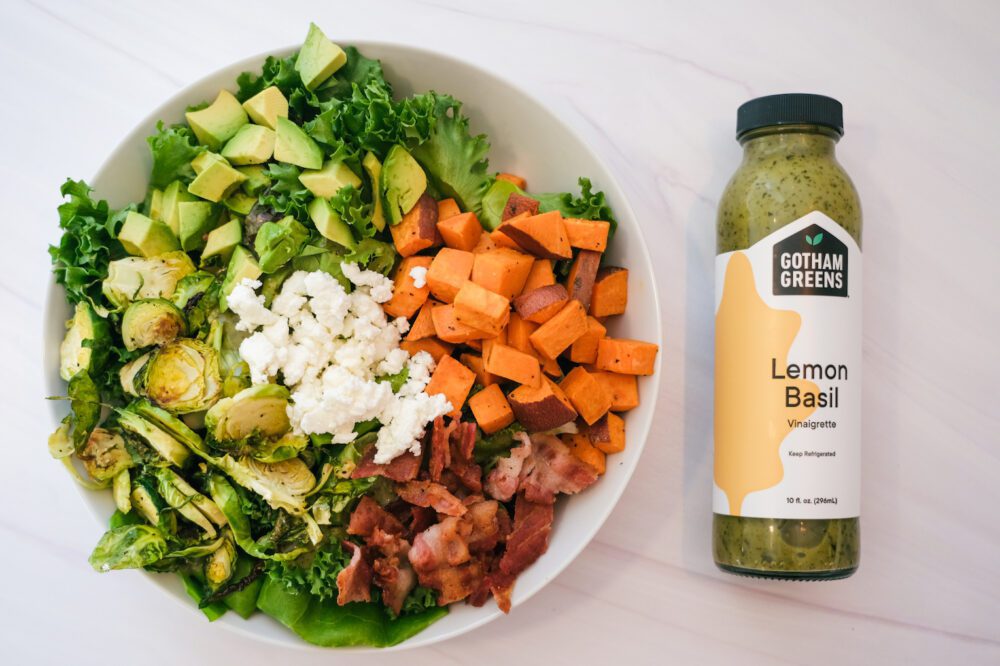 salad topped with sweet potato, brussels sprouts, bacon, goat cheese, gotham greens lemon basil dressing and avocado