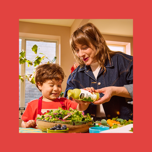 Gotham Greens + Sesame Street collaboration: a mom pours Avocado Lime Ranch for her son into a bowl of salad